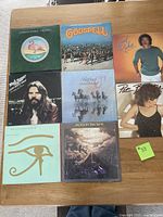 Top-down photo of 8 assorted used vinyl albums showing cover artwork of Christopher Cross, Godspell soundtrack, Lionel Richie, Jackson Browne, Pat Benatar, Alan Parsons Project, and Bob Seger albums.