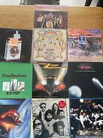 Overview of 9 vinyl album covers arranged in a 3x3 grid on a wooden table, showing bands and album art.