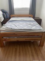 Full view of the pine bed frame with mattress, showing headboard, footboard, and bedding.