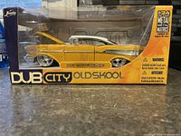 Front and side view of the yellow 1957 Chevy Bel Air die cast car in original Dub City Old Skool box with clear window showing detailed model inside.