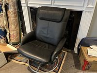 Front and slight angle view of black leather swivel recliner chair with cushioned headrest.