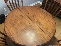 Top view of round oak dining table showing wood grain and center split for inserting leafs.