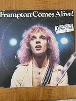 Front cover of Frampton Comes Alive vinyl album showing image of Peter Frampton with long hair and guitar. Includes sticker noting 2 records in set.