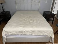 Overview of assembled queen bed showing white metal headboard, mattress and box spring