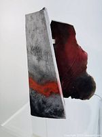 Side view of the abstract pottery piece showing rough textured surface, gray with a red streak, irregular edges