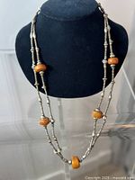 Front full view of the antique Ethiopian silver and amber necklace displayed on black bust showing entire length and bead arrangement.