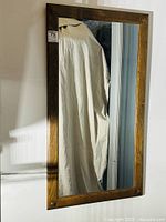 Full view of the antique oak framed hanging mirror showing the rectangular reflective glass and wooden frame with knob detailing at corners.