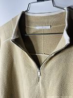 Close-up photo showing the zipper and collar area of the beige knit pullover sweater for men.
