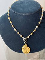 Full view of the necklace displayed on a black neck stand showing round beads and fossil pendant.