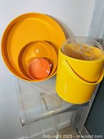 Photo showing all four items: ice bucket with handle and lid, and three melamine trays nested inside each other.