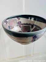 Front view of the mid-century modern pottery bowl showing round shape, flared rim, and abstract glaze pattern with muted blue, purple, and beige tones.