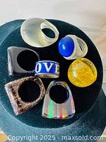 Top-down view of seven costume rings, showing colors and design variety.
