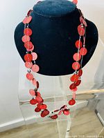 Front view of the custom made necklace on a black display bust showing three wires with red wafer beads.