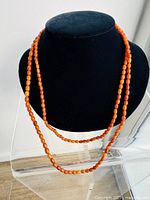 Photo showing the full length of the double-wrapped amber necklace on a black display stand