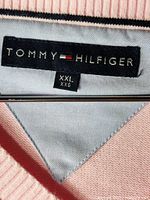 Close-up of the Tommy Hilfiger brand label on the sweater's interior neckline, showing size XXL and the 100% cotton material indication.