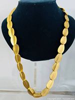 Front view of vintage Alfred Sung gold tone necklace displayed on black bust, showing full length and curved teardrop shaped segments.