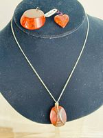 Image showing three amber pendants including an oval pendant on a chain, a round pendant, and a heart-shaped pendant on black display bust.