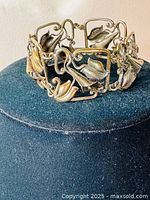 Full view of the vintage silver bracelet displayed on a dark stand, showing openwork lily flower motifs.