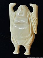 Close-up photo of the vintage Happy Buddha brooch on a black background showing the carving detail and size.