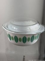White mudglass bowl with green leaf pattern and clear glass lid shown from side angle