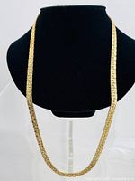 Front view of the gold tone vintage necklace on a black bust, showing full length and texture.