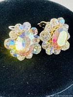 Close-up front view of the pair of Sherman rhinestone clip-on earrings showing the central oval and surrounding smaller rhinestones with gold-tone metal setting.