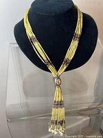 Front view of the yellow beaded tribal necklace showing the sterling pendant and pearl-tipped tassels.