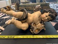 Lateral view of putto holding lyre with measuring tape showing approx 18" length