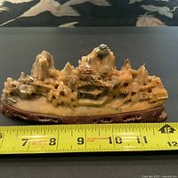 Front view of the carved hardstone sculpture with measuring tape showing approximately 11 inches in length