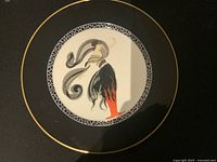 Top view of the large ERTE charger plate with black and gold rim and the figure artwork in the center.