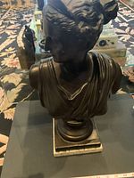 Front view of dark metal goddess bust on marble base