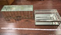 Glass jewelry box and glassed planter side by side on wooden floor with measuring tape indicating size.