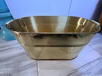 Front perspective of a large oval vintage brass tub showing two handles and overall condition.