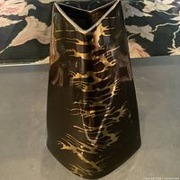 Full view of the black metal vase with gold abstract patterns showing overall shape and color.