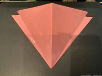 Front view of the pink triangular geometric ceramic wall pocket with distinct central ridge and angular side fins.