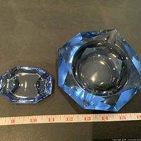 Photo showing two blue heavy cut crystal pieces: a smaller ashtray on left and a larger dish on right, with a tape measure below showing approximate size.