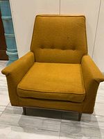 Front view showing tufted back, seat cushion, armrests and leg profile