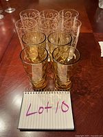 Top down view showing six clear spiral patterned glasses behind four amber yellow glasses on a wooden table.