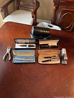 Four pen sets, stapler, hole punch, electric pencil sharpener on table