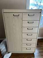 Full view of tall dresser showing 6 drawers on the right and a cabinet door on the left with metal handles