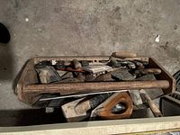 Full view of wooden toolbox filled with various vintage drywall tools including trowels, knives, and floats.