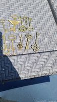 10 gold-colored ornamental steampunk style keys displayed on woven surface outdoors