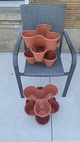 Front view of six stackable plastic planters arranged on a chair, showing their shape and size.