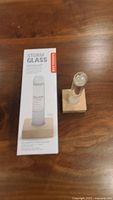 Glass storm glass weather predictor with wooden base and original packaging on wooden surface.