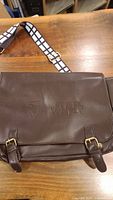 Front flap of brown messenger bag showing embossed Blue Jays and Star Wars logos
