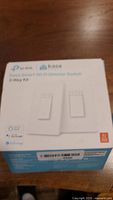 Box of TP-Link Kasa Smart Wi-Fi 3-Way Dimmer Switch Kit showing front label with product name and icons for voice assistant compatibility.