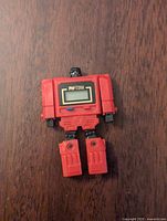 Red robot figure standing upright showing the watch display on the chest reading 'TITAN'.