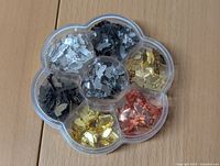 Top view of a plastic flower-shaped divided container with silver, black, gold, and copper butterfly charms