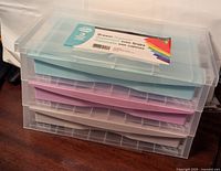 Stacked view of three new plastic drawer organizers in blue, purple, and gray colors with transparent lids.