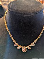 Choker necklace displayed on a black velvet bust showing the front design with iridescent beads and gold-tone metal.